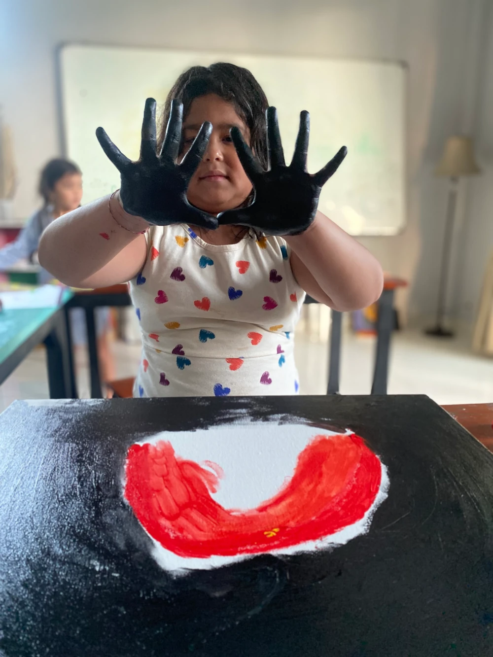 A girl is showing off the dark paint on her hands after completing a hand painting