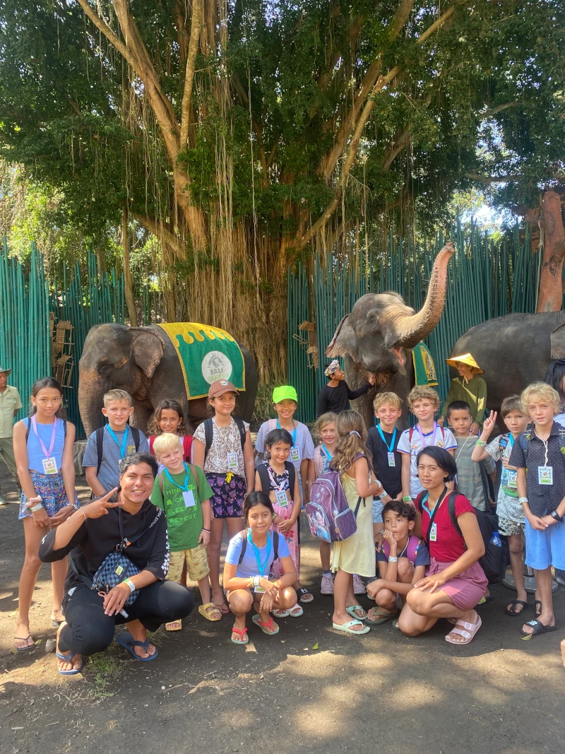 A photo of a large group of children on a school trip to an elephant park